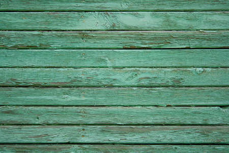 Wooden fence painted in green, peeling cracked paintの写真素材