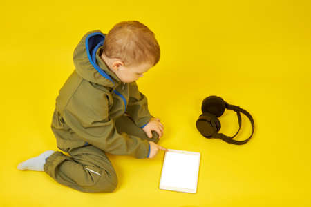 The child uses a tablet and headphones for online games, communicates with friends, and learns...