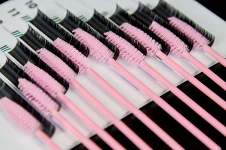 A tablet with false eyelashes and brushes on a black background. Cosmetic accessories for eyelash extensionsの写真素材