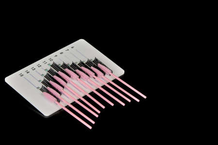 A tablet with false eyelashes and brushes on a black background. Cosmetic accessories for eyelash...