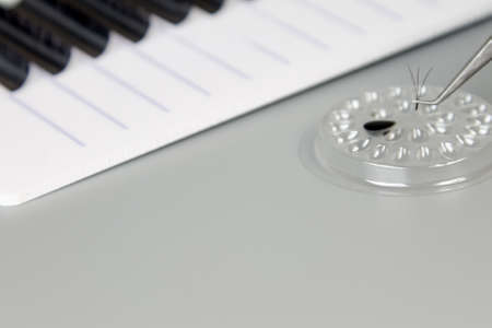 A tablet with false eyelashes, glue and tweezers on a gray background. Cosmetic accessories for eyelash extensionsの写真素材