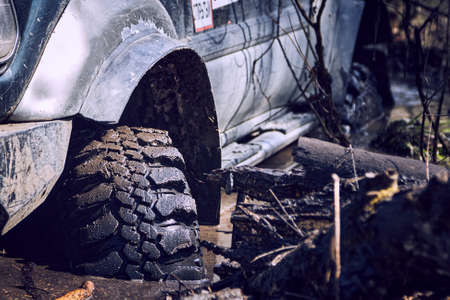 The 4x4 SUV is stuck in the mud. The wheels of the SUV are in dirty water. The concept of adventure...