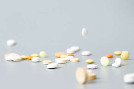 Multicolored pills are showered from above on a gray background. Rain of medicineの写真素材