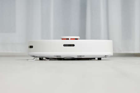 The white robot vacuum cleaner effectively cleans the floor in automatic mode. Smart Home...