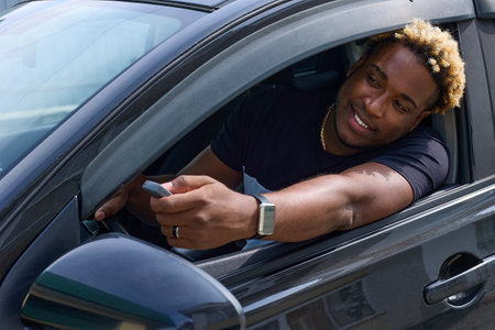 Man with a toothy smile in the car uses the remote control of the gate to open the automatic door...