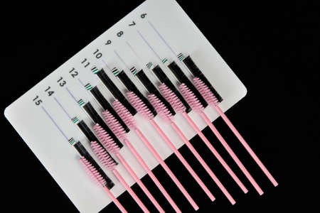 A tablet with false eyelashes and brushes on a black background. Cosmetic accessories for eyelash...