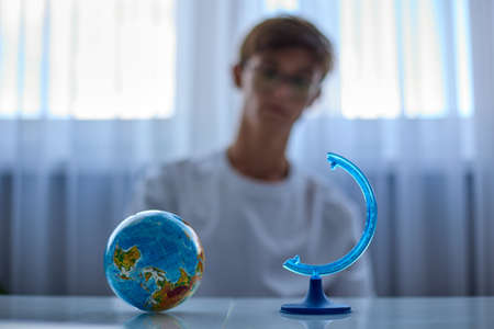 Broken globe and a depressed teenager with glasses in the background. A mans world has collapsed,...