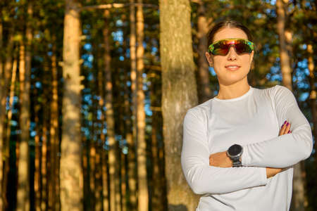 Happy athletic woman in sports glasses is getting ready to start training outdoors and get a boost of energy for the whole day. Concept of sports and a healthy lifestyleの写真素材