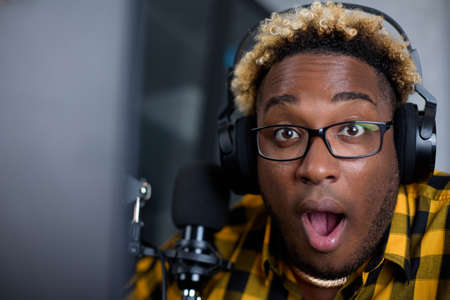 Portrait of an African radio host with glasses and with microphone, who opened his mouth in surprise...