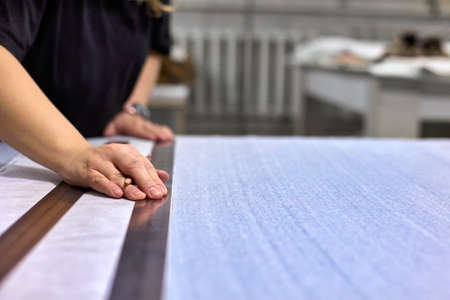 Process of cutting and sewing. Close-up of the seamstress hands make a drawing on the fabric using a...