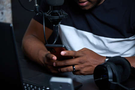 Close up image of mens hands typing on a smartphone in a chat. A black guy sits at an office desk, works online, communicates with pen palsの写真素材