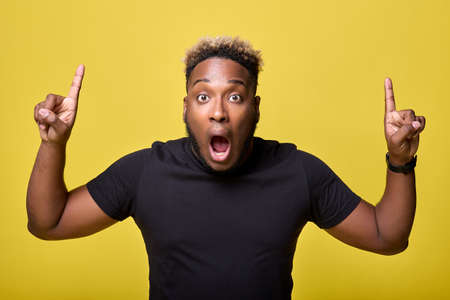 Shocked by what he saw, the black man indicates the maximum discounts on everyday clothes. Athletic physique African-American surprised by prices, promotes saleの写真素材