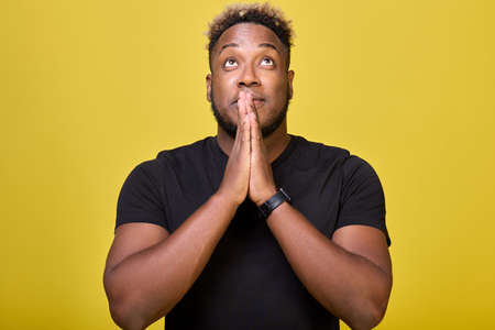 A black man athletic begs God to fulfill his long-held dream. A rather agitated modern African-American holds his hands with his palms together, prays for good luck, dreams of winning.の写真素材