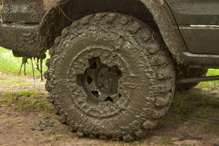 Very dirty off road wheel is on the road . Four wheel drive car after an off-road trip. Traveling...