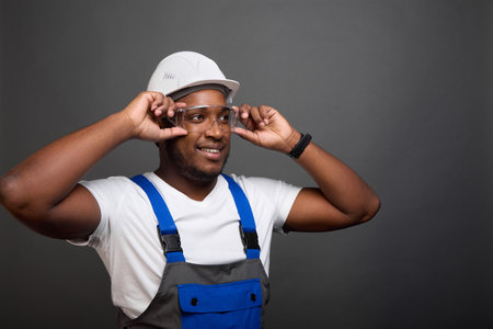 A modern professional architect carefully adjusts his goggles while on a construction site. A young foreman tries on new glasses to comply with safety precautions at the construction siteの写真素材