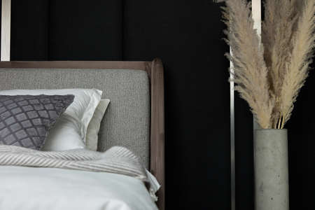 Modern design of bedroom is made in black and brown tones. In bedroom with dark walls there is large...