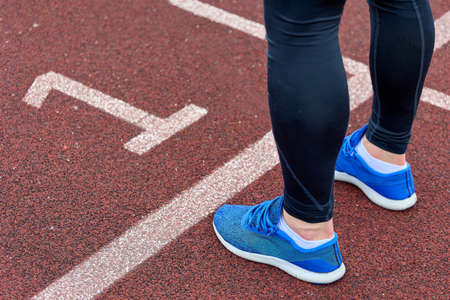 An athlete runner trains in the stadium, standing at the white line on track number one. Close-up of...