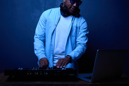 Professional DJ in headphones works in a club behind a professional music installation. Brutal...