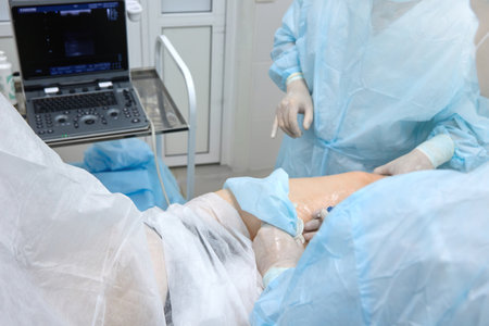 Patient on operating table is covered with medical sheets, surgeon is preparing to insert a catheter...