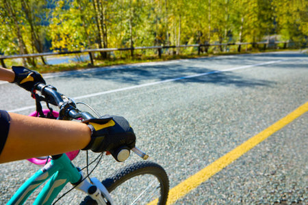 Cyclist in protective gloves rides along the track along the yellow markings in sunny clear weather....