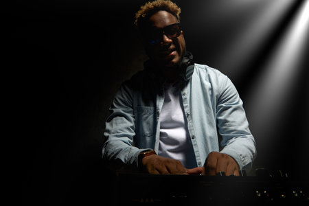 English speaking African American at the DJ booth. A black guy performs electronic music in a disco....