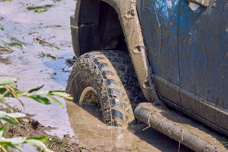 Close-up of a blue 4x4 off-road car stuck in a swamp during extreme competitions. Off-road car racing. SUV in action. Get off the beaten track.の写真素材
