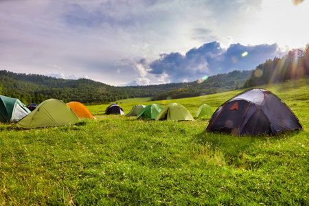 Tourist tent in the camp among the meadows in the mountains. Outdoor camping with beautiful sunshine in the morningの写真素材