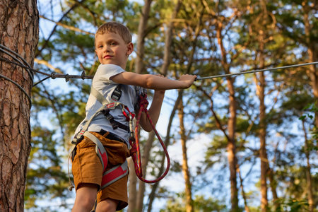 Caucasian boy looks into the camera, the child is ready to go through a new stage of the rope park...