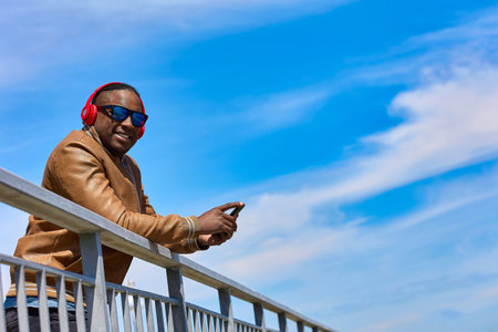 Smiling African man uses a smartphone to receive a love text message on a dating site while standing...