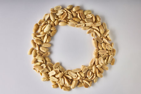 Delicious, healthy dried peanuts are laid out in a circle in the form of a letter on a white...