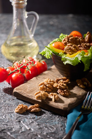 Beautiful stylish serving of healthy delicious fresh vegetables on a gray table along with nuts. A salad of vegetables and walnuts is prepared in the restaurant for visitorsの写真素材