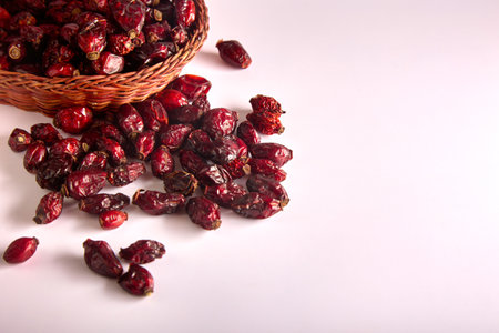 Large red dry rosehip berries are scattered from wicker dishes on a white background. Seasonal superfood in the form of rosehips with health benefits and disease preventionの写真素材