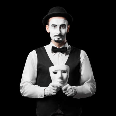Mime artist holding white mask Isolated on blackの写真素材