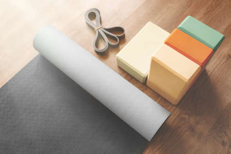 Beautiful yoga equipment composition of mat, bricks and rubber band. Morning mood, sunlight. Close...
