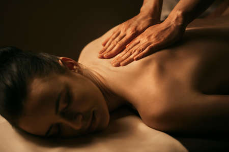 The beautiful girl has massage. Authentic image of luxury spa treatment. Warm colors, charming light.の写真素材