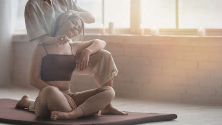 Young beautiful girl has Thai massage at spa salon with professional masseur. Morning tranquil mood. Copy spaceの写真素材