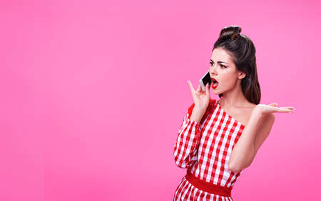 Beautiful young brunette dressed in retro style argues on the phone