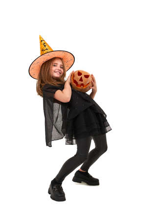 Joyful girl in witch costume holds pumpkinの写真素材