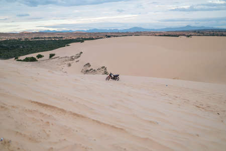Picturesque view of parked motorbike on sandy dunes in desert. Sunny day during summer vacation. Sand dunes. Motorcycle in desert.の写真素材