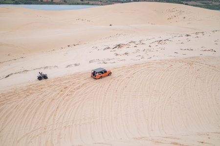 Picturesque view of big car driving on sandy dunes and tire tracks on sand on sunny day during summer vacation. Sand dunes. Hight quality photo.の写真素材