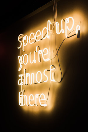 Neon yellow lettering on the wall speed up, you are almost there. High quality photo. neon lettering on the wallの写真素材