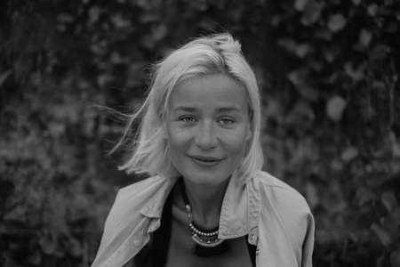 Black and white close-up portrait of smiling pretty caucasian young woman with blond hair, wearing casual clothing and stylish necklace.の写真素材