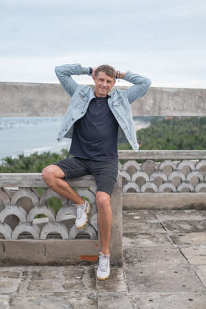 Portrait of young handsome Caucasian man in casual wearing and denim jacket, sitting and smiling....