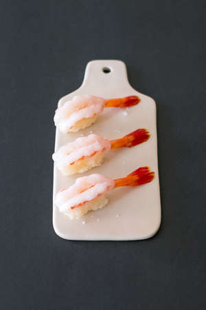 Prawn sushi in japanese restaurant. Sushi - ama Ebi Nigiri on white board isolated on black background. Shrimp sushi. High quality photoの写真素材