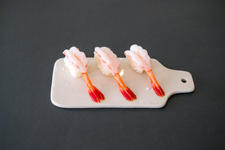 Prawn sushi in japanese restaurant. Sushi - ama Ebi Nigiri on white board isolated on black background. Shrimp sushi. High quality photoの写真素材
