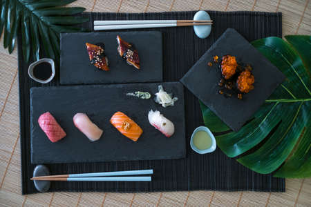 Japanese food. Delicious sushi set with various kinds of Nigiri sushi with salmon, tuna, backed eel, red salmon caviar served on black slate boardsの写真素材