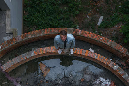 Young handsome Caucasian man in casual wearing standing on the abandoned construction site and looking at camera with copy space. view from aboveの写真素材