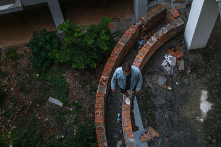 Young handsome Caucasian man in casual wearing and denim jacket walking on the abandoned construction site. view from aboveの写真素材