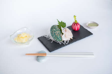 Decorated sashimi on black tray in Japanese restaurant. Perfectly served sushi with sauce and chopsticks. Isolated on white. Photo for the menu.の写真素材