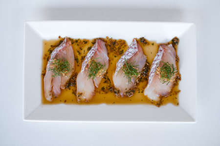 Sea bass sashimi with the sauce on white plate on white background. Isolated on white. Japanese restaurant. Japanese traditional food. Raw fish.の写真素材